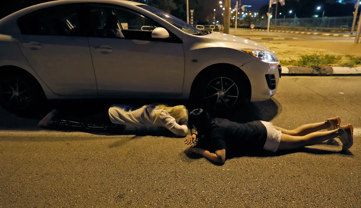 Warga Israel tiarap di jalan raya saat berlindung dari serangan roket Palestina di Kota Ashdod, Israel, Minggu (5/5/2019). Saling serang antara militan Gaza dengan tentara Israel telah menewaskan 23 orang Palestina dan 4 Israel. (Ahmad GHARABLI/AFP)