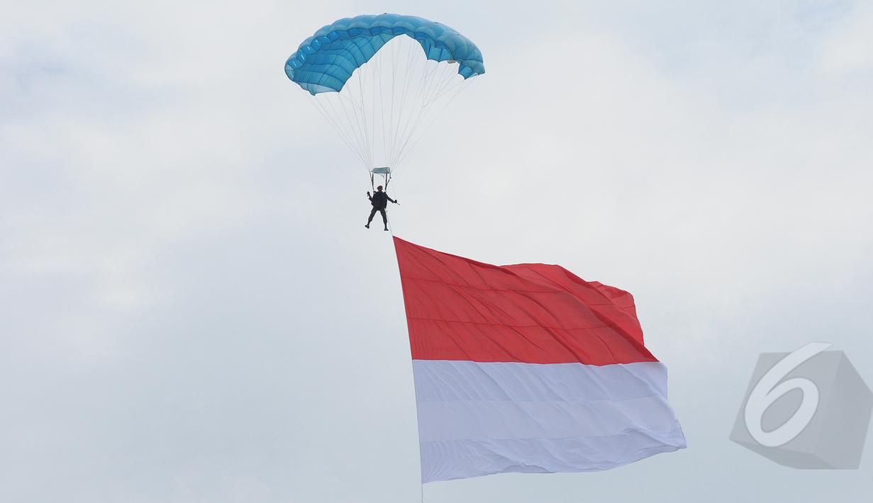 Aksi terjun payung prajurit TNI AU membawa bendera merah putih saat peringatan HUT ke-69 TNI AU Tahun 2015 di Lanud Halim Perdanakusuma, Jakarta, Kamis (9/4/2015). Acara tersebut menampilkan demo darat dan atraksi udara. (Liputan6.com/Herman Zakharia)