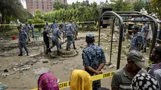 Warga berkumpul dan menyaksikan aktivitas sejumlah personel Angkatan Udara Bangladesh membersihkan puing-puing saat memeriksa lokasi jatuhnya pesawat latih milik Angkatan Udara Bangladesh yang menimpa kompleks sekolah di Dhaka, 22 Juli 2025. (MUNIR UZ ZAMAN/AFP)
