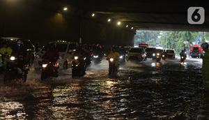 Pengendara sepeda motor menerjang banjir yang merendam terowongan di Cawang, Jakarta, Jumat (19/2/2021). Hujan yang turun sejak semalam membuat sejumlah jalanan di Ibu Kota tergenang banjir dengan ketinggian sekitar 30-50 cm. (merdeka.com/Imam Buhori)