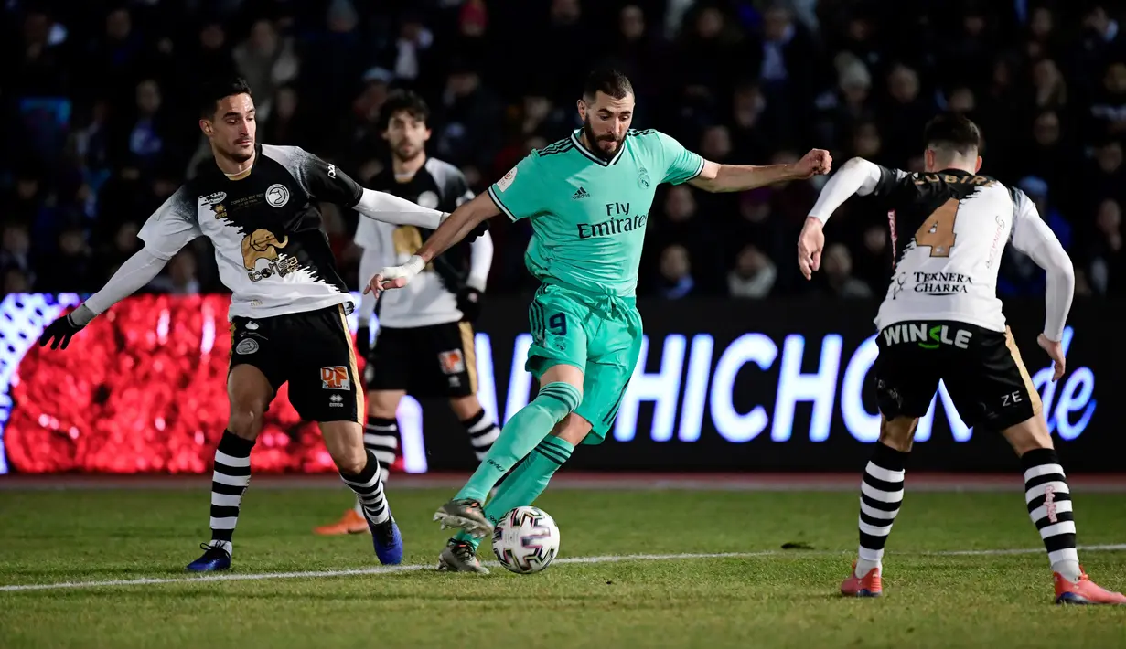 Striker Real Madrid, Karim Benzema berebut bola dengan bek Unionistas de Salamanca, Inigo Zubiri pada pertandingan babak ke-32 besar Copa del Rey 2019-2020 di Pistas del Helmantico, Rabu (22/1/2020). Madrid harus berjuang keras untuk menang 3-1 atas tim divisi tiga, Unionistas. (JAVIER SORIANO/AFP)