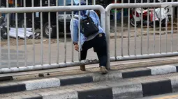 Seorang wanita menerobos pagar pembatas jalan di kawasan Pasar Minggu, Jakarta, Kamis (5/4). Kondisi Jembatan Penyeberangan Orang (JPO) yang tak kunjung diperbaiki membuat warga nekat menyeberang lewat celah pagar pembatas (Liputan6.com/Immanuel Antonius)