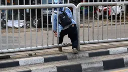 Seorang wanita menerobos pagar pembatas jalan di kawasan Pasar Minggu, Jakarta, Kamis (5/4). Kondisi Jembatan Penyeberangan Orang (JPO) yang tak kunjung diperbaiki membuat warga nekat menyeberang lewat celah pagar pembatas (Liputan6.com/Immanuel Antonius)