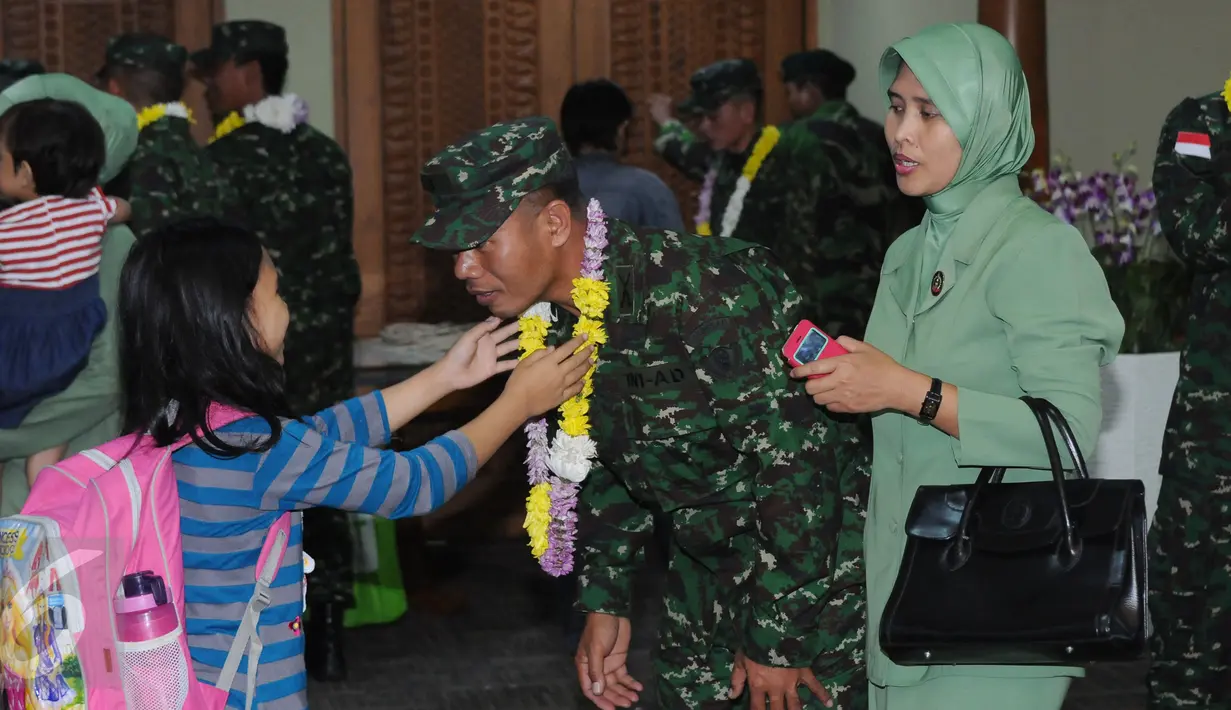 Seorang anak mengalungkan bunga kepada sang ayah usai usai penyambutan kedatangan kontingen AASAM di Bandara Soetta, Banten, Senin (23/5/2016). TNI AD menjadi juara umum AASAM 2016 yang digelar di Australia. (Liputan6.com/Helmi Fithriansyah)