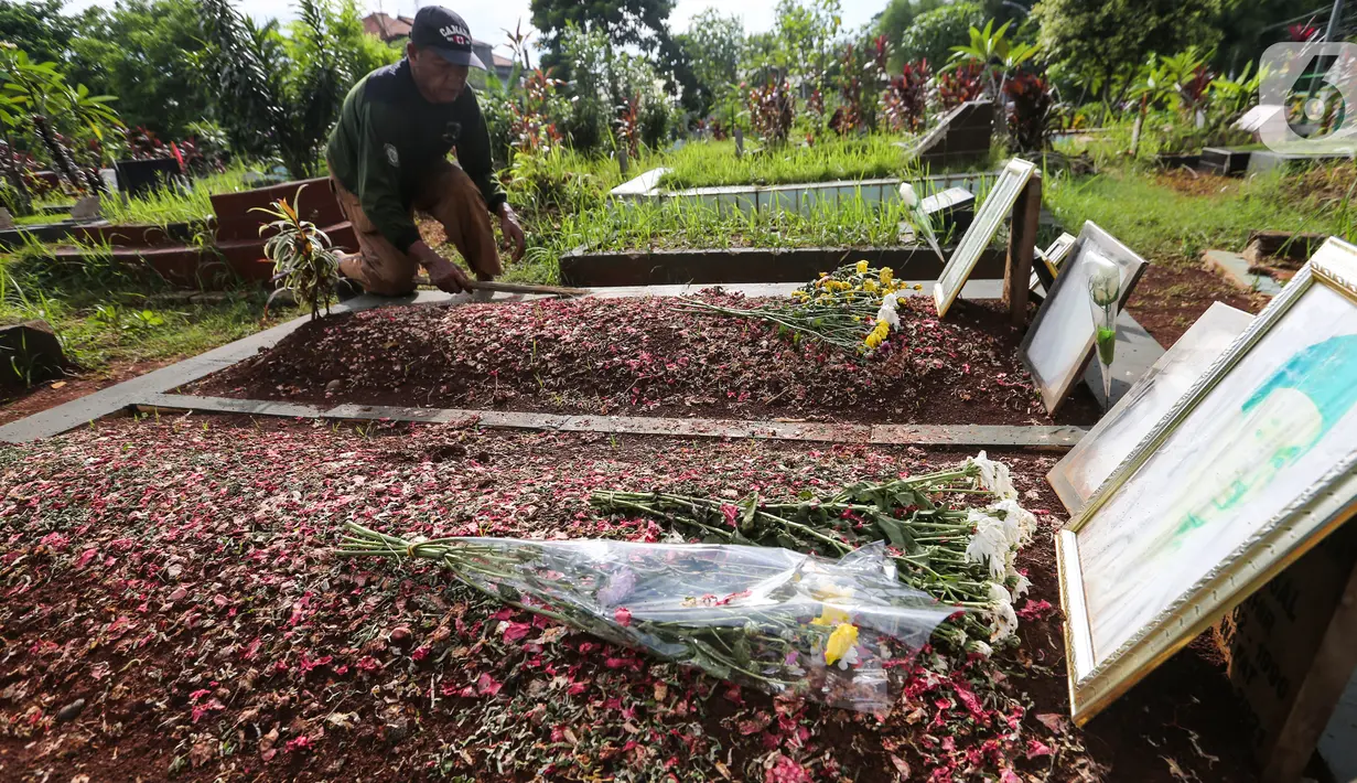 Pengurus makam membersihkan makam Vanessa Angel dan Bibi Ardiansyah di TPU Taman Makam Islam Malaka Blok D, Pesanggrahan, Jakarta, Senin (7/02/2022). Berdasarkan Perda Jakarta No.3/2007 Pasal 26 pemindahan dan penggalian jenazah dapat dilakukan atas permintaan ahli waris. (Liputan6.com/Fery Pradolo)