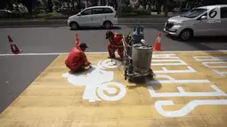 Pekerja mengecat rambu jalur kuning khusus sepeda motor di Jalan Medan Merdeka, Jakarta, Selasa (16/1). Penerapan jalur kuning sepeda motor di kawasan tersebut akan dimulai per 15 Januari 2018. (Liputan6.com/Arya Manggala)