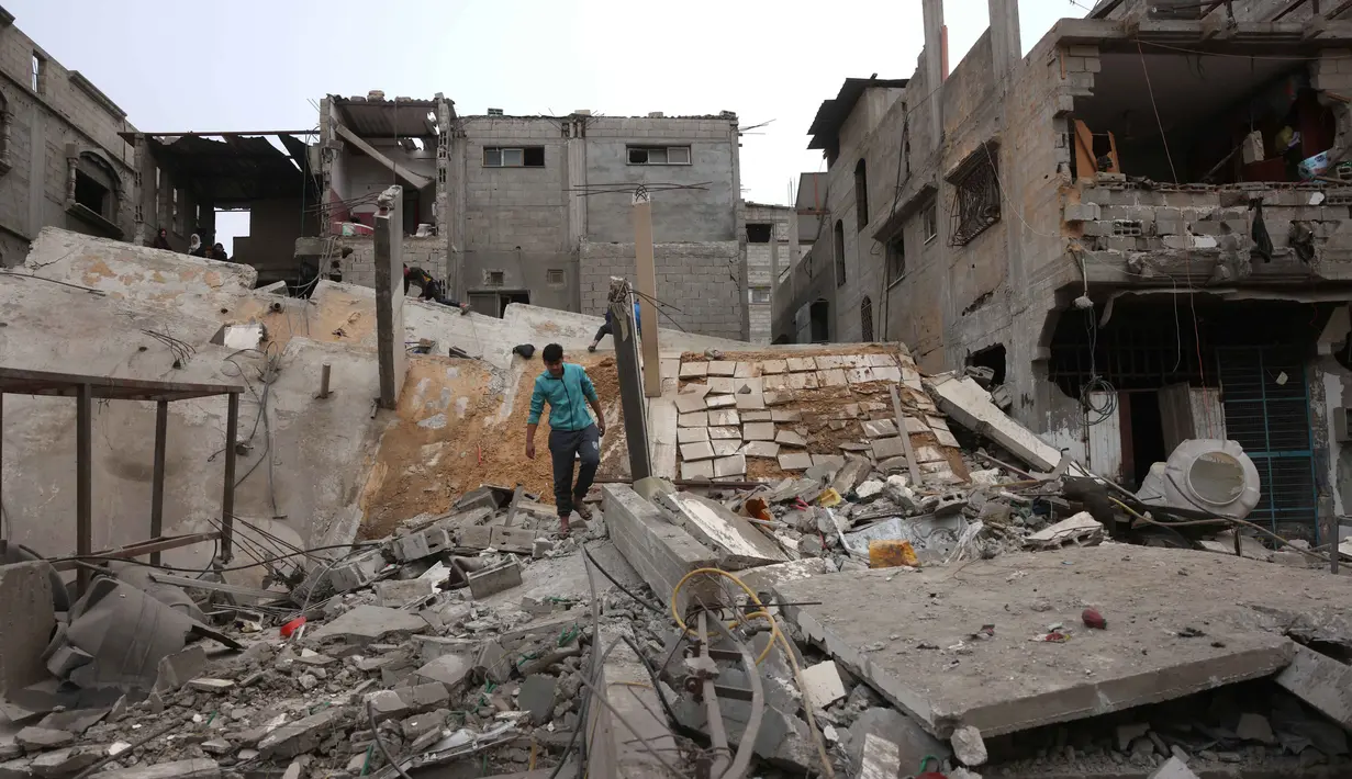 Seorang pria Palestina yang mengungsi berjalan di atas puing-puing setelah pesawat Israel menargetkan sebuah rumah berlantai lima tadi malam, di Khan Yunis, Jalur Gaza selatan pada Kamis 6 Februari 2026. Ketegangan di Jalur Gaza kembali memanas. (Bashar Taleb/AFP)