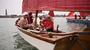 Anggota asosiasi pelayaran budaya mengambil bagian dalam acara Regatta Merah di Venesia, Italia, Minggu (20/6/2021). Regatta Merah diselenggarakan oleh seniman AS Melissa Mc Gill. (MARCO BERTORELLO/AFP)