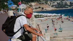 Seorang pria yang memakai masker mengunjungi sebuah pantai yang ada di Nice, Prancis selatan, pada Rabu (22/7/2020). Banyak pengunjung memadati Nice selama liburan musim panas di tengah pandemi COVID-19. (Xinhua/Serge Haouzi)
