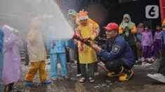Petugas pemadam kebakaran (Damkar) Kota Tangerang membantu siswa Taman Kanak-Kanak (TK) menyemprotkan air untuk memadamkan api saat edukasi pengenalan profesi Damkar di Kota Tangerang, Banten (22/11/2023). (Liputan6.com/Angga Yuniar)