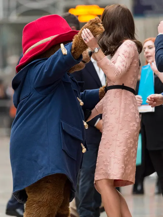 Kate Middleton asyik berdansa dengan seorang aktor yang mengenakan kostum Paddington di stasiun kereta Paddington, London, Senin (16/10). Seperti biasa, kate tampil anggun dalam balutan gaun pink salem rancangan Orla Kiely. (Jonathan Brady/Pool via AP)