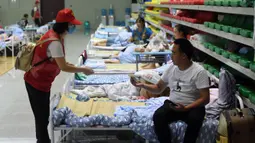 Sukarelawan memberikan buklet instruksi keselamatan kepada penduduk desa di tempat pengungsian sementara Sekolah Menengah No.168, Hefei, Provinsi Anhui, China, Rabu (29/7/2020). Lebih dari 300 penduduk desa di Kota Sanhe, Hefei, dievakuasi ke sekolah itu akibat terdampak banjir. (Xinhua/Liu Junxi)