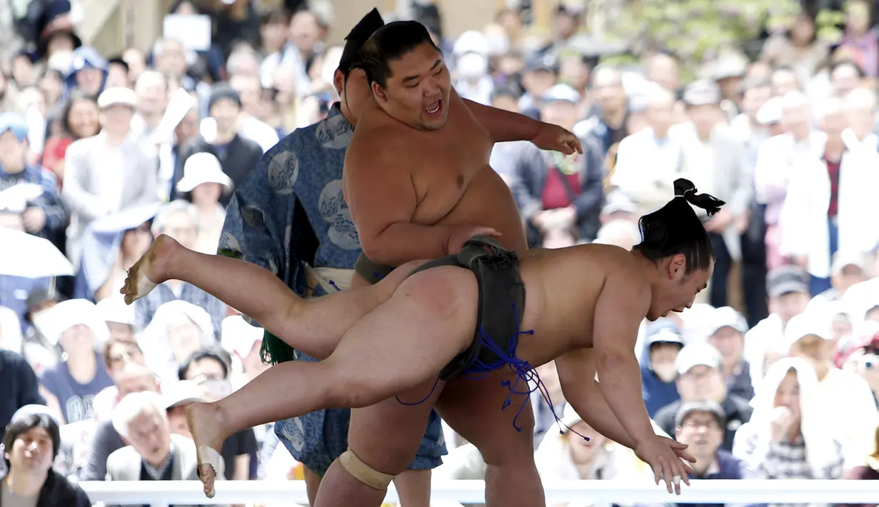 Seorang pesumo berhasil menjatuhkan lawannya dalam turnamen Sumo, Honozumo di Kuil Yasukuni, Tokyo, Senin (18/4). Selain menjadi ajang kejuaraan olahraga tradisional jepang, kejuaraan tahunan itu juga menjadi daya tarik wisata. (REUTERS/Yuya Shino)