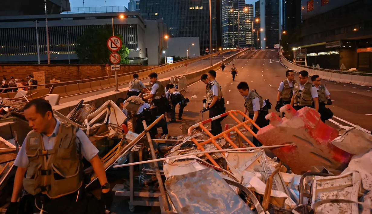 Petugas polisi membersihkan barikade yang dibuat demonstran setelah aksi menolak RUU ekstradisi di Hong Kong (13/6/2019). Aksi tersebut berujung bentrok antara polisi dan warga dimana puluhan ribu orang memblokir jalan-jalan di kota tersebut. (AFP Photo/Hector Retamal)