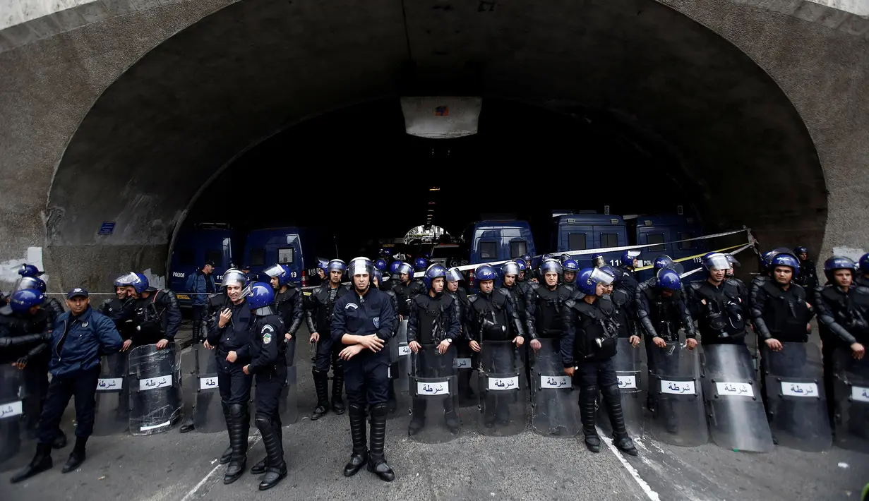 Polisi menyaksikan ratusan ribu demonstran berunjuk rasa di Aljir, Aljazair, Jumat (19/4). Polisi dikerahkan di seluruh kota untuk mengamankan unjuk rasa. (REUTERS/Ramzi Boudina)