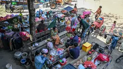 Sementara itu, puluhan ribu orang telah meninggalkan rumah mereka di dekat perbatasan untuk mencari tempat penampungan yang aman. Tampak dalam foto, warga berkumpul di luar sebuah kuil setelah dievakuasi menyusul bentrokan di sepanjang perbatasan Kamboja-Thailand, di provinsi Siem Reap pada Selasa 9 Desember 2025. (TANG CHHIN SOTHY/AFP)