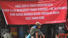 Seorang ibu menggendong anaknya berjalan di depan spanduk penolakan di kawasan jalan Mangga Besar, Jakarta, Senin (22/8). Spanduk itu dipasang warga RW2 Kelurahan Mangga Besar sebagai aksi menolak penggusuran rumah mereka. (Liputan6.com/Gempur M Surya)