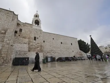 Seorang biarawan Kristen berjalan menjelang Natal di luar Gereja Kelahiran Yesus di kota Bethlehem, Tepi Barat pada 22 Desember 2022. Menjelang perayaan Natal, Kota Bethlehem sudah bersolek. Dekorasi liburan dan cerita kelahiran Yesus menghiasi kota itu. (AFP/Hazem Bader)