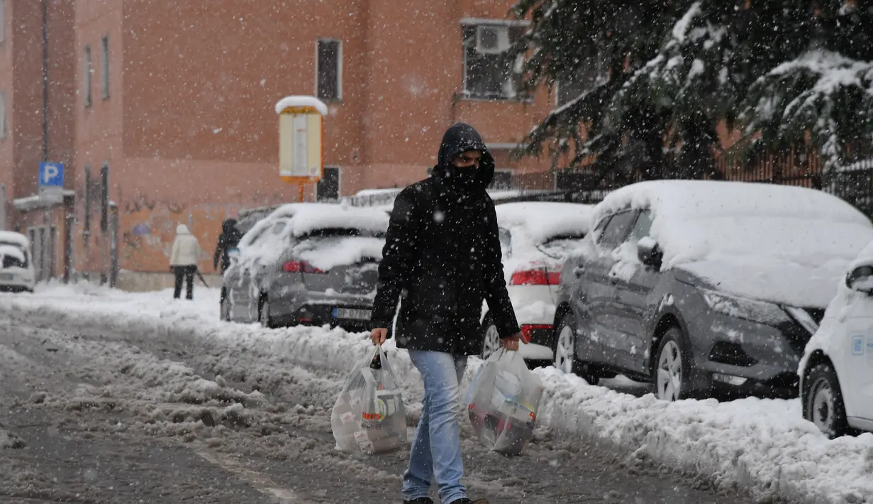 Seorang pria berjalan di tengah salju di Milan, Italia utara (28/12/2020). Hujan salju mengguyur Milan pada Senin (28/12). (Xinhua/Daniele Mascolo)