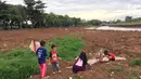 Anak-anak bermain di sekitar kawasan Danau Setu Babakan yang mengering di Jakarta, Jumat (5/1). Mereka bermain sambil mengisi waktu libur sekolah. (Liputan6.com/Immnanuel Antonius)