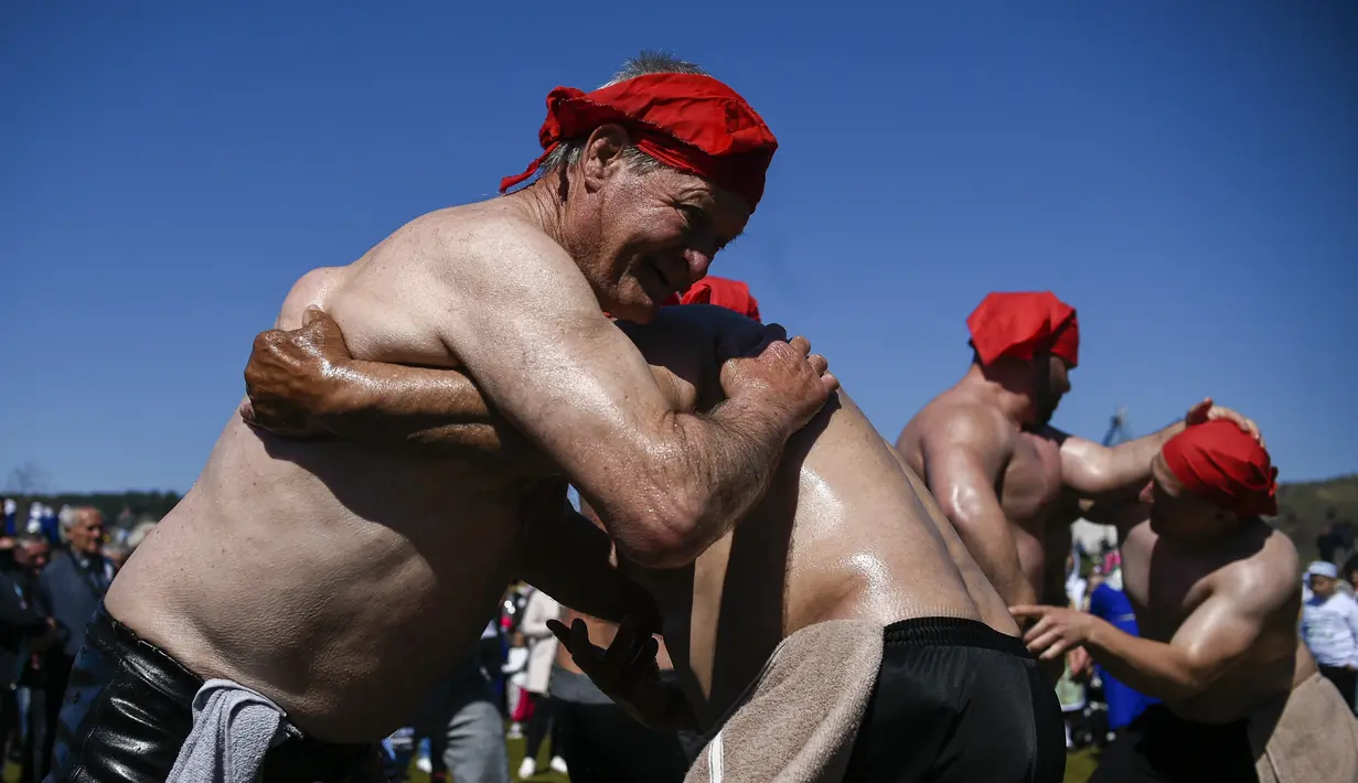 Pegulat minyak muslim Bulgaria bertarung selama upacara sunat massal untuk anak laki-laki di Desa Ribnovo, 11 April 2021. Penduduk Desa Ribnovo adalah muslim berbahasa Bulgaria, kadang-kadang disebut sebagai "Pomaks" atau "orang yang menderita". (Nikolay DOYCHINOV/AFP)
