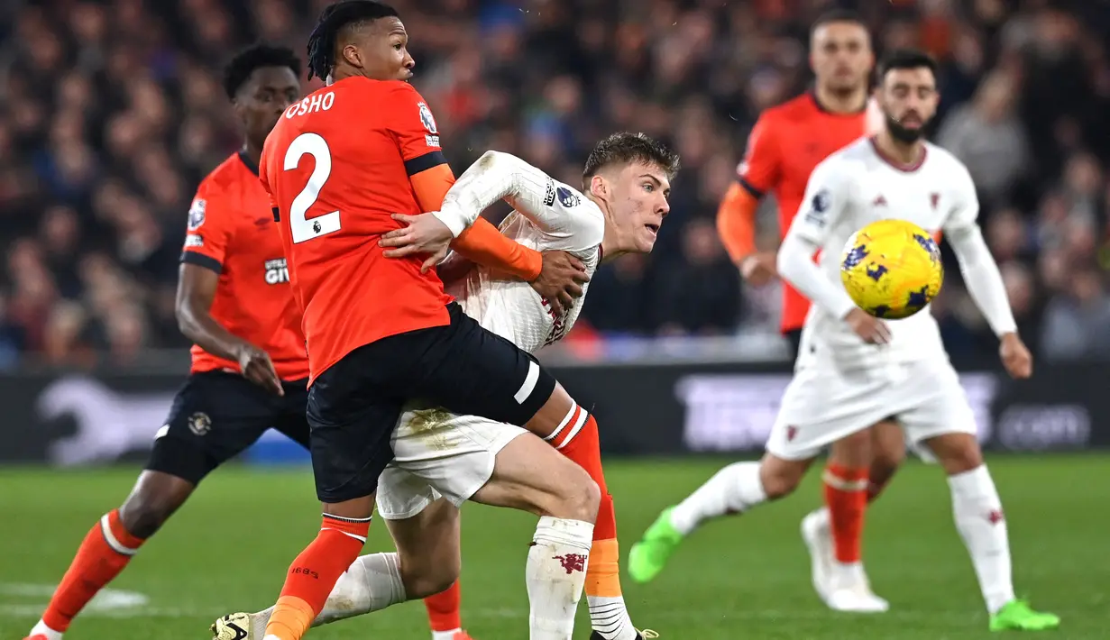 Pemain Manchester United, Rasmus Hojlund, berusaha melewati pemain Luton Town, Gabriel Osho, dalam duel pekan ke-25 Premier League di Kenilworth Road, Minggu (18/2/2024). (AFP/Glyn Kirk)