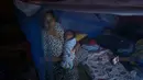 Beberapa kawasan permukiman warga yang kini mengungsi di tenda-tenda darurat dilaporkan masih gelap gulita. Tampak dalam foto, Lia Minarti, 35 tahun, menggendong bayinya, Muhammad Hafid, yang hampir berusia satu bulan, di dalam kelambu di tenda darurat setelah kehilangan rumahnya akibat banjir bandang sekitar tiga minggu sebelumnya, di Aceh Tamiang, pada Selasa 16 Desember 2025. (Yasuyoshi Chiba/AFP)