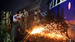 Pekerja melakukan pengelasan saat proses evakuasi sebuah kereta api yang tergelincir di Negara Bagian Uttar Pradesh, India, Minggu (20/8). Lima gerbong kereta Kalinga-Utkal Express keluar dari jalur dan beberapa gerbong saling bertumpuk. (AP/Altaf Qadri)