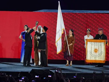 Gubernur DKI Jakarta Anies Baswedan menyerahkan obor Asian Games kepada Wali Kota Hangzhou China saat penutupan Asian Games 2018 di Stadion Utama GBK, Jakarta, Minggu (2/9). (Merdeka.com/Imam Buhori)