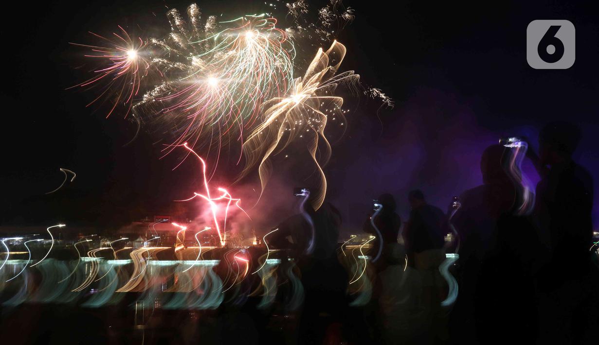 Warga menyaksikan pesta kembang api saat perayaan malam puncak Tahun Baru 2023 di Danau Archipelago, Taman Mini Indonesia Indah (TMII), Jakarta, Minggu (1/1/2023). Sebelumnya, Pemprov DKI Jakarta menunjuk TMII untuk menjadi pusat perayaan tahun baru 2023 di Jakarta. (Liputan6.com/Herman Zakharia)