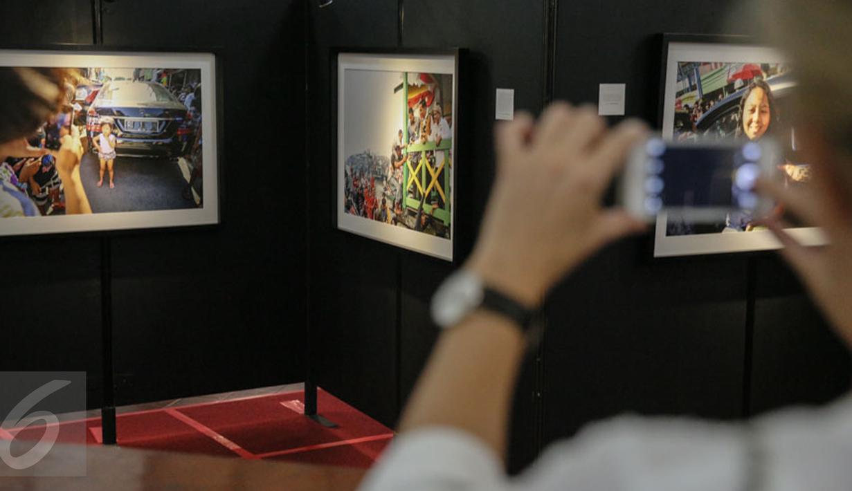 Pengunjung memotret karya foto yang dipajang pada pameran foto jurnalistik Setahun Kerja Jokowi-JK di Museum Bank Mandiri, Jakarta, Jumat (18/12). Pameran itu mengangkat berbagai kegiatan Kabinet Kerja selama setahun. (Liputan6.com/Faizal Fanani)