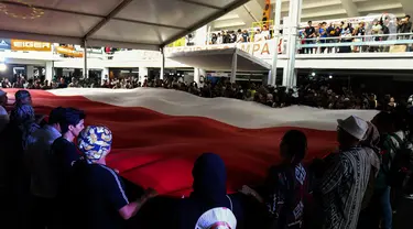 Pengunjung pameran produk berkegiatan di alam bebas atau Indofest 2023 membentangkan bendera Merah Putih di pelataran Istora Gelora Bung Karno, Jakarta, Kamis (1/6/2023). (Liputan6.com/Herman Zakharia)