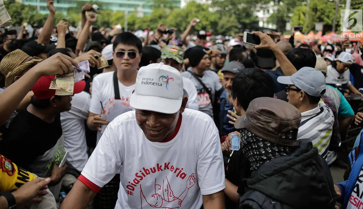 mengeluarkan sejumlah uang dan menunjukkannya ke arah peserta jalan sehat #DiaSibukKerja ketika bertemu pada kegiatan Car Free Day di sisi barat Bundaran HI, Jakarta, Minggu (29/4). (Liputan6.com/Faizal Fanani)