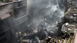 Petugas penyelamat berkumpul di lokasi jatuhnya pesawat Pakistan International Airlines di Karachi, Pakistan, Jumat (22/5/2020). Proses evakuasi baru berakhir pada Sabtu dini hari. (Rizwan TABASSUM/AFP)