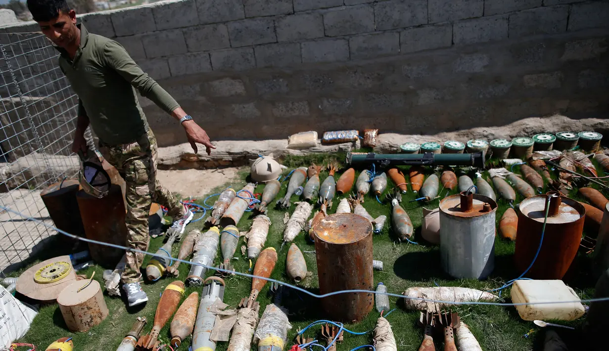 Tentara Irak menunjukkan amunisi, mortir dan bahan peledak lainnya milik ISIS yang berhasil ditemukan di wilayah barat Mosul, Kamis (6/4). (AFP Photo / Ahmad Gharabli)