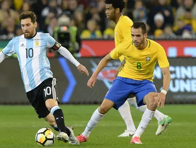 Penyerang Argentina, Lionel Messi (kiri) berusaha mengiring bola dari kawalan gelandang Brasil, Renato Augusto pada laga persahabatan di MCG di Melbourne (9/6). Argentina menang atas Brasil dengan skor 1-0. (AFP Photo/Mal Fairclough)