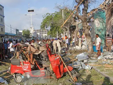 Warga berkumpul di lokasi ledakan di luar Hotel Weheliye, Jalan Maka al Mukaram, Mogadishu, Somalia, (22/3). Sedikitnya 14 orang tewas dan 10 lainnya terluka dalam ledakan bom mobil tersebut. (AP Foto/Farah Abdi Warsameh)