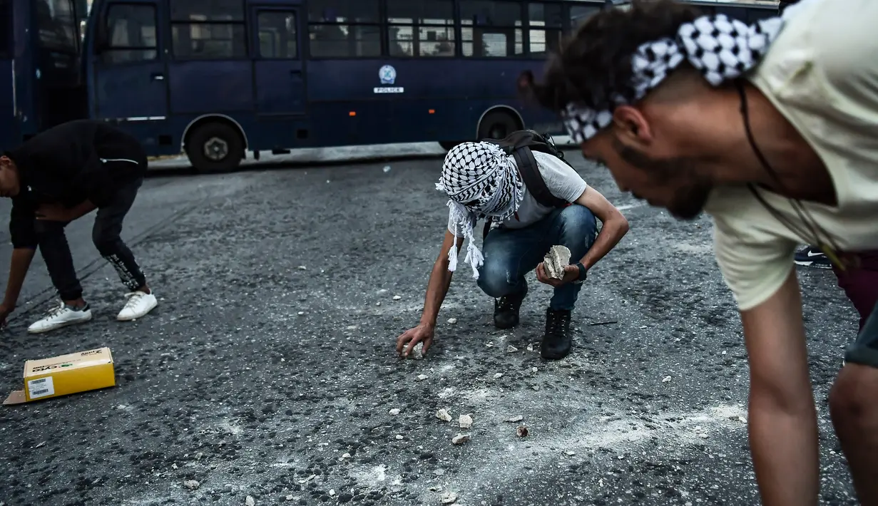 Pengunjuk rasa mengambil batu untuk dilempar ke kedutaan Israel di Athena, Yunani, Selasa (15/5). Mereka mengecam Israel menembak mati puluhan warga Palestina di perbatasan Gaza yang berunjuk rasa menentang pembukaan kedubes AS. (AFP/Aris MESSINIS)