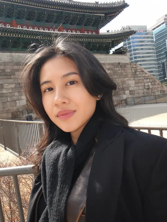 Paduan ini membuat tampilan tetap feminin tanpa kehilangan nuansa edgy. Sementara itu, crossbody bag dengan rantai perak melengkapi outfit dengan sentuhan modern yang praktis dipakai saat traveling.