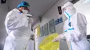 Petugas laboratorium melepaskan pakaian pelindung di sebuah laboratorium di Shenyang, provinsi Liaoning timur laut China, Rabu (12/2/2020). WHO kini tidak lagi menyebut virus yang merebak di China sebagai Virus Corona Baru. (STR/AFP)