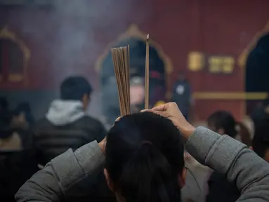 Seorang wanita berdoa untuk keberuntungan pada hari kelima Tahun Baru Imlek di Yonghegong, atau Kuil Lama di Beijing (9/2). Warga China di seluruh dunia menyambut Tahun Babi pada 5 Februari.  (AFP Photo/Nicolas Asfouri)