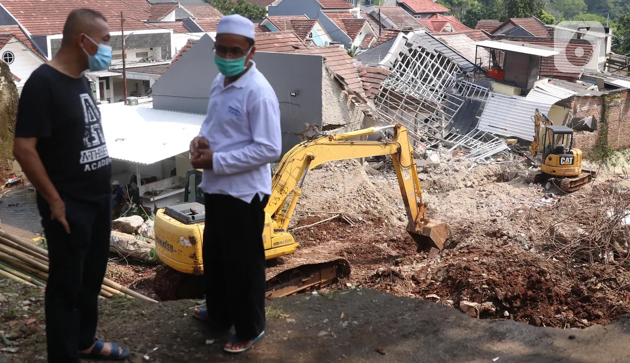 Warga berada dekat rumah yang hancur tertimpa tanah longsor di Perumahan Nerada Estate Ciputat, Tangerang Selatan, Sabtu (12/6/2021). Tidak ada korban jiwa dalam peristiwa longsor yang menimpa sejumlah rumah akibat hujan deras yang terus menerus di kawasan tersebut. (Liputan6.com/Angga Yuniar)