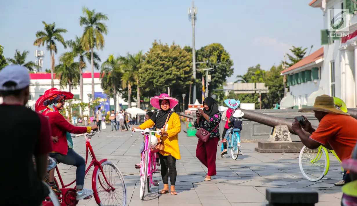 Wisatawan berfoto sambil bermain sepeda di kawasan Museum Fatahillah, Jakarta, Jumat (6/10). Usai revitalisasi kini museum tersebut terlihat lebih bersih dan bebas dari pedagang liar kaki lima. (Liputan6.com/Faizal Fanani)