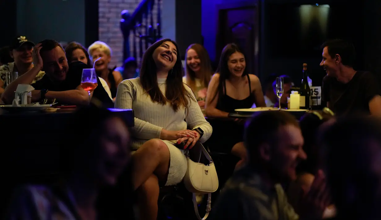 Orang-orang menghadiri pertunjukan stand-up comedy Serhiy Lipko di Kyiv, Ukraina, 11 Juni 2022. Perang Ukraina tidak terlalu lucu, tetapi orang-orang di sana belajar menertawakan kengerian itu semua untuk tetap waras dalam konflik yang telah menewaskan puluhan ribu orang tersebut. (AP Photo/Natacha Pisarenko)