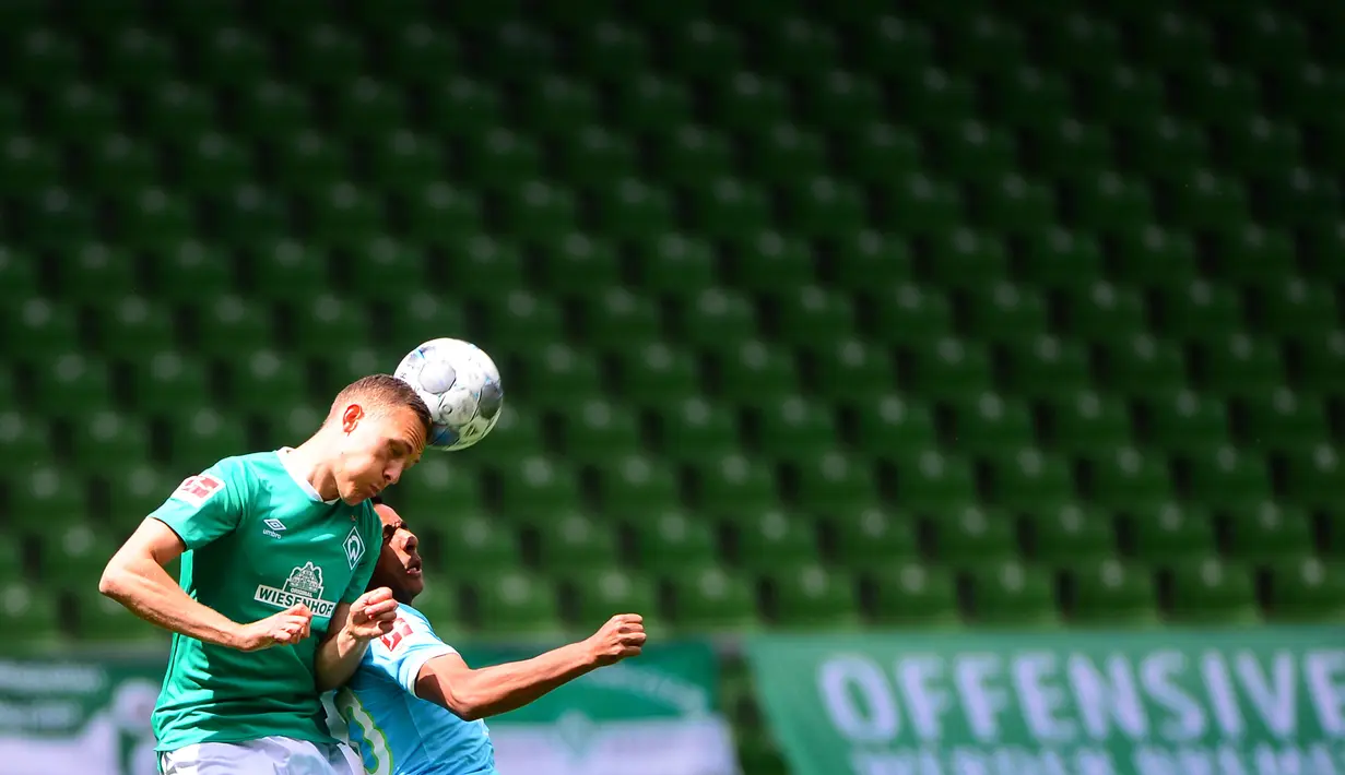 Pemain Werder Bremen,  Maximilian Eggestein, berebut bola dengan pemain Wolfsburg, Jerome Roussillon, pada laga Bundesliga di Weserstadion Minggu (7/6/2020). Werder Bremen takluk 0-1 dari Wolfsburg. (AFP/Patrik Stollarz)