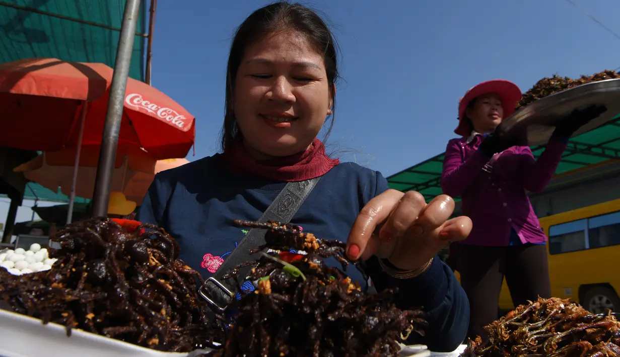 Pedagang Kamboja menyiapkan tarantula goreng untuk dijual di wilayah Skun, Provinsi Kampong Cham, 4 Desember 2019. Daerah yang kerap dijuluki "Spiderville" tersebut menjadi tempat menarik bagi para turis berburu aping, camilan tradisional dari tarantula ini. (TANG CHHIN Sothy / AFP)