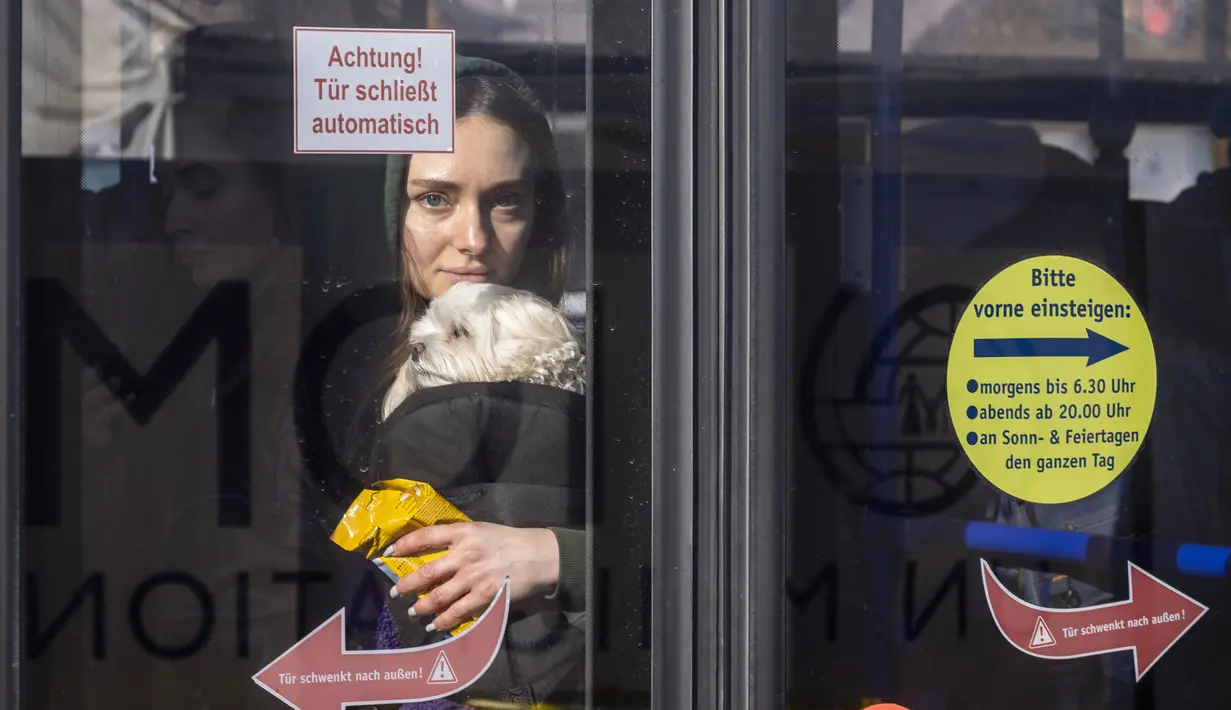 Dascha dari Kiev menggendong anjingnya di bus ke Przemysl setelah melintasi perbatasan Ukraina-Polandia di perbatasan Medyka, Polandia, 17 Maret 2022. Lebih dari tiga juta warga Ukraina telah melarikan diri melintasi perbatasan, kebanyakan wanita dan anak-anak, menurut PBB. (Wojtek RADWANSKI/AFP)