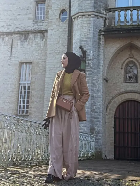 Blazer tersebut dipadukan inner sweater kuning dan kerudung hitam. Irish juga mengenakan bawahan celana panjang loose warna Ivory serta sneaker hitam. [@_irishbella_]