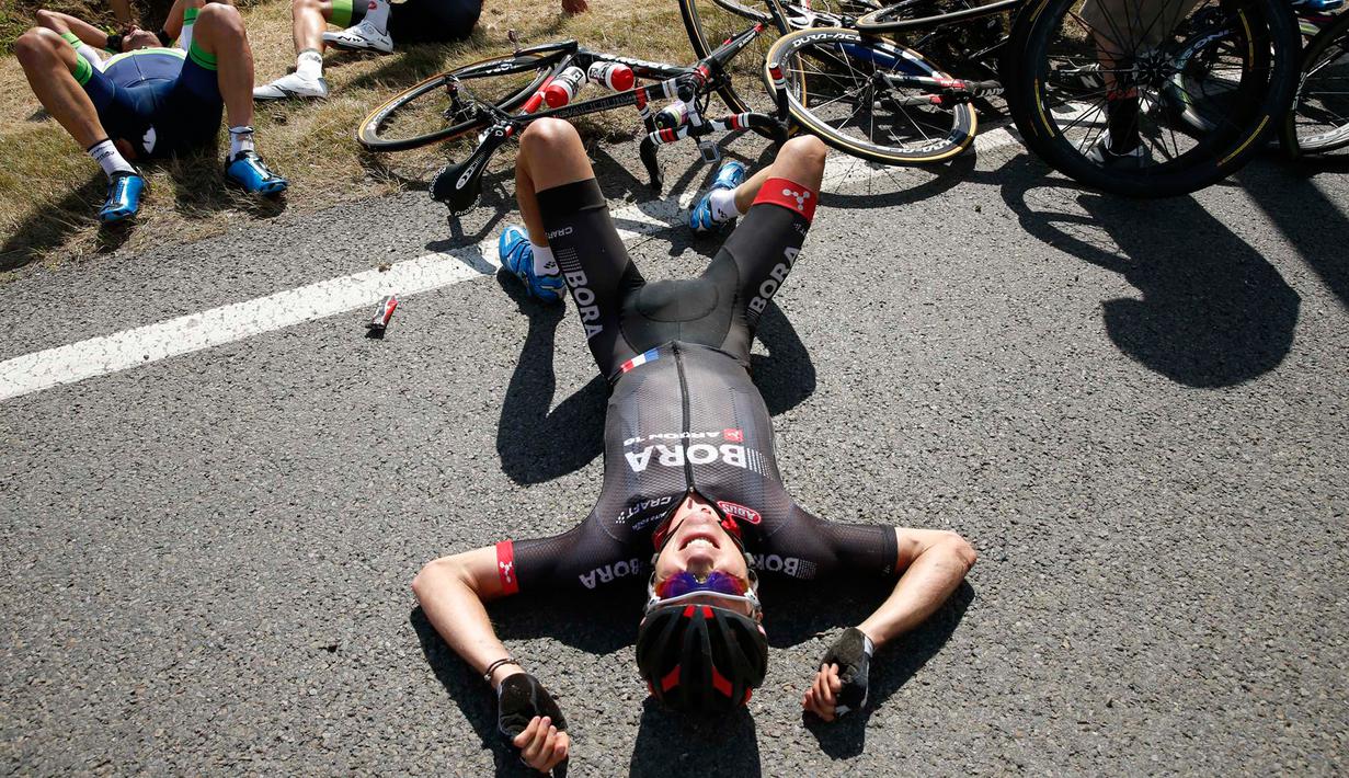Seorang pembalap terlihat berbaring usai insiden kecelakaan yang melibatkan puluhan pebalap sepeda saat babak ketiga Tour de France dari Anvers ke Huy di Belgia, Senin (6/7/2015). (REUTERS/Eric Gaillard)