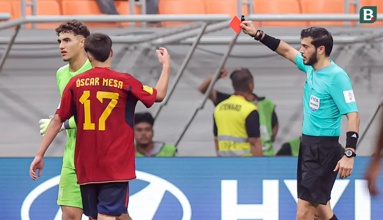 Wasit Omar Al Ali (kanan), memberikan kartu merah kepada kiper Timnas Spanyol U-17, Raul Jimenez (kiri), setelah menjatuhkan pemain Jerman U-17, Bilal Yalcinkaya, saat pertandingan perempat final Piala Dunia U-17 2023 yang berlangsung di Jakarta International Stadium, Jumat (24/11/2023). (Bola.com/Bagaskara Lazuardi)